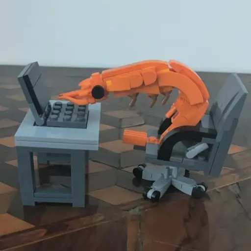 Lego sculpture of a shrimp typing on a computer