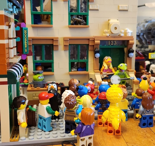 A couple of the muppets jamming in front of Sesame Street characters. 